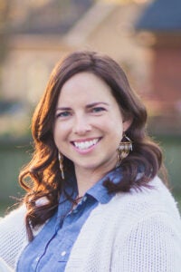 A woman smiles for her outdoor headshot photo.