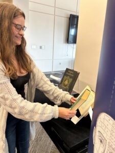 A person with long hair and glasses is reading a book.