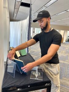A person setting up the NIH Legacy of Physiognomy exhibit, placing a book on a display stand
