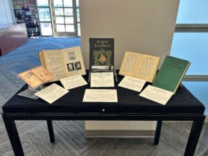 A display of historical books arranged on a black table with informational cards in front of each book.